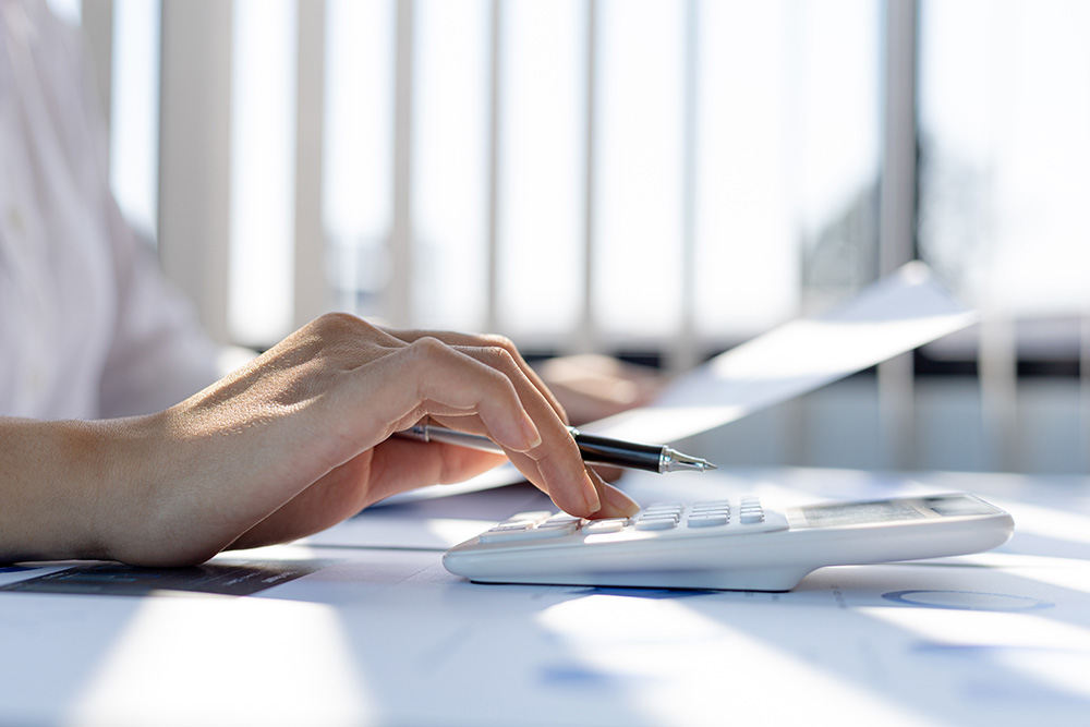 A business woman using a calculator to calculate numbers on a co